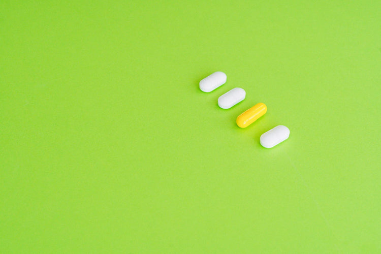 Capsulas multivitaminicas sobre superficie verde